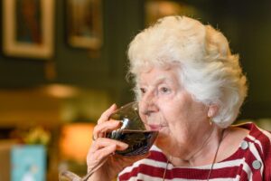 Senior citizen drinking glass of wine with faraway expression