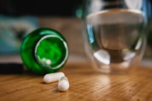 Generic pills next to glass of clear liquid representing medication to help with alcohol withdrawal