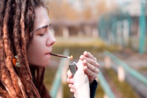 Young woman lighting joint outdoors