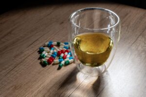 Amber liquid representing alcohol next to pills representing trazodone on table