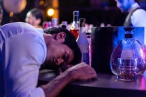 Man slumped over at bar after drinking heavy amount of alcohol